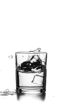Cube of ice thrown into a glass with liquid Stock Photos