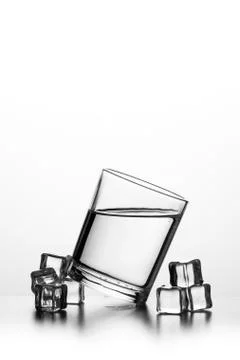 Cube of ice thrown into a glass with liquid Stock Photos