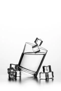 Cube of ice thrown into a glass with liquid Фото
