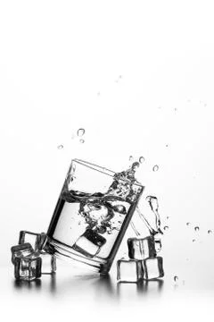 Cube of ice thrown into a glass with liquid Stock Photos