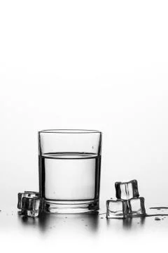 Cube of ice thrown into a glass with liquid Stock Photos