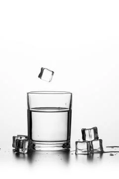 Cube of ice thrown into a glass with liquid Stock Photos