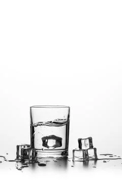 Cube of ice thrown into a glass with liquid Stock Photos