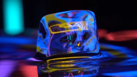 Cube oof ice in yellow neon lighting rotating in water Stock Footage 106829944