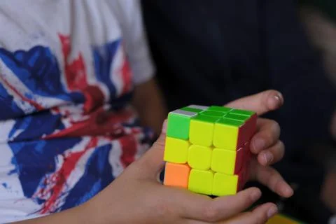Cube puzzle with multi-colored faces in the hands of a child of school age Stock Photos