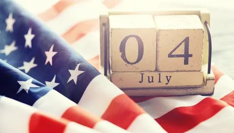 Cube shape calendar for July 04 on wooden table on usa flag background Stock Photos