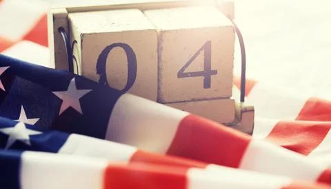 Cube shape calendar for July 04 on wooden table on usa flag background Stock Photos