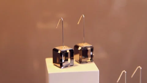 Cube-shaped glass earrings displayed in a store display or exhibition Stock Footage 247900858