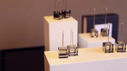 Cube-shaped glass earrings displayed in a store display or exhibition Stock Footage 247900859