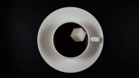 A cube of sugar falls into the coffee in a cup. Slow mo, top view Stock Footage 74377807
