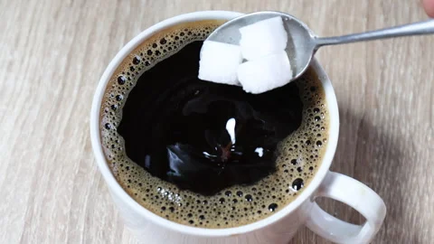 Cube sugar pouring into black coffee in white cup, illustrating taste Stock Footage 328244340