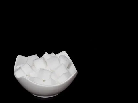 Cube sugar, sugar cubes in an angular shell in front of black background Stock Photos