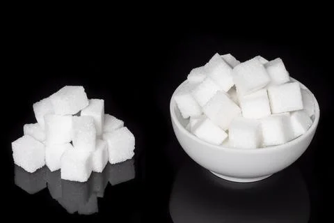Cube sugar, sugar cubes in a round dish, and stacked against a black backgr.. Stock Photos