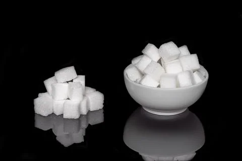 Cube sugar, sugar cubes in a round dish, and stacked against a black backgr.. Stock Photos