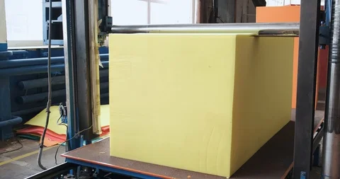 Cube of synthetic foam on machine conveyor, knife cuts foam into thin layers Stock Footage 128786980