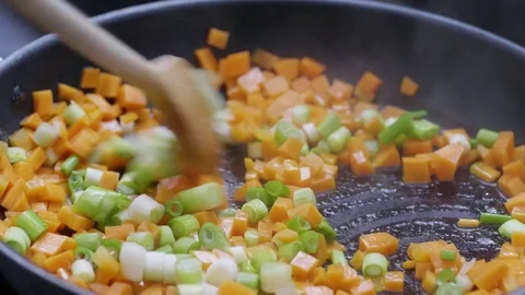 Cubed carrots and sliced spring onions being sauteed in a frying pan Stock Footage 84493980
