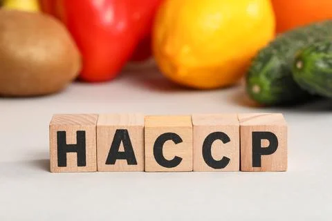 Cubes with abbreviation of HAZARD ANALYSIS AND CRITICAL POINTS with fruits an Stock Photos