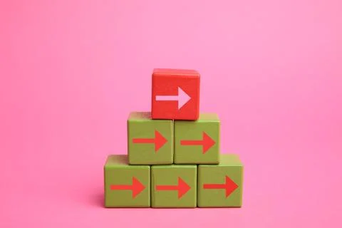 Cubes with arrows and red one on top against pink background Stock Photos