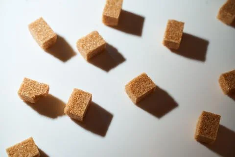 Cubes of cane sugar on a white background with a shadow. Top view. Stock Photos