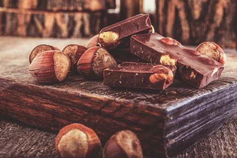 Cubes of chocolate with hazelnuts or nuts around Stock Photos