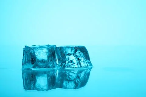 Cubes of clear ice on light blue background, closeup. Space for text 库存照片