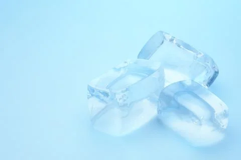 Cubes of clear ice on light blue background, closeup. Space for text Stock Photos