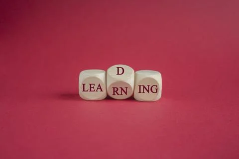 Cubes form the words learning and leading. Beautiful red background. Stock Photos
