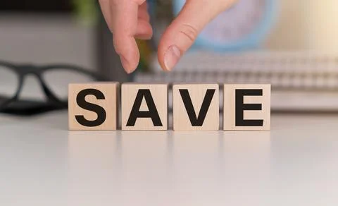The cubes make up the word SAVE, the cubes are on a white notepad on the ta.. Stock Photos