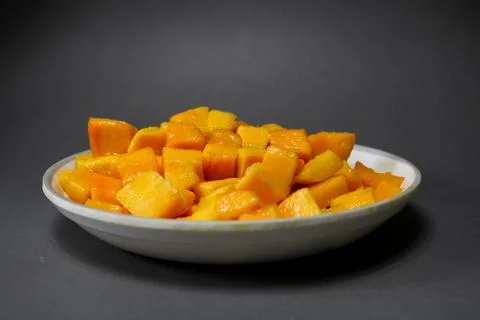 Cubes of Mango in a white plate on isolated black background Stock Photos