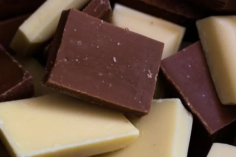Cubes of milk and white chocolate mix together. Stock Photos