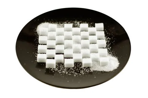 Cubes of refined sugar laid in a pattern on a black plate, cryst Stock Photos