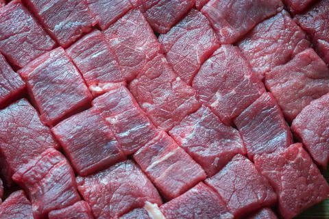 Cubes of sliced raw roast beef meat on wooden cutting board closeup Foto stock