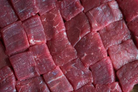 Cubes of sliced raw roast beef meat on wooden cutting board closeup Fotos de archivo