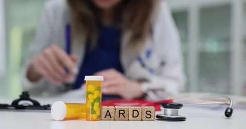 Cubes spell ARDS near pill bottle and doctor in bright lab Stock Footage 314117606