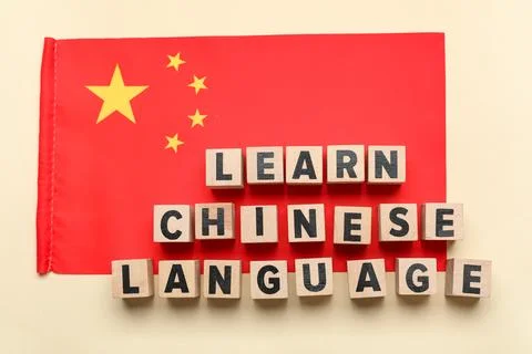 Cubes with text LEARN CHINESE LANGUAGE and flag on beige background Stock Photos