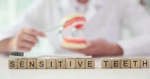 Cubes with words Sensitive Teeth against dentist with jaw model Stock Footage 280571215