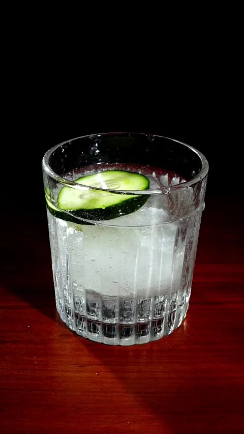 Cucumber Slice Falling into Gin Tonic Glass Slow Motion Stock Footage 324599916