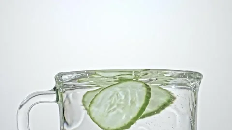 Cucumber slices falling into water Stock Footage 241348994