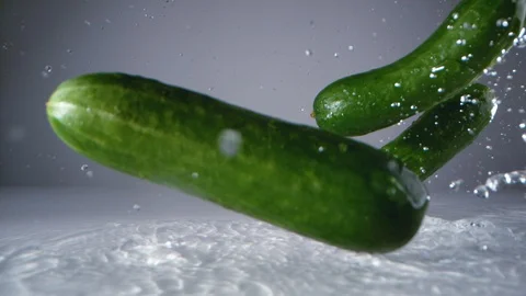 Cucumbers falling on water surface. Slow Motion. Stock Footage 128771771