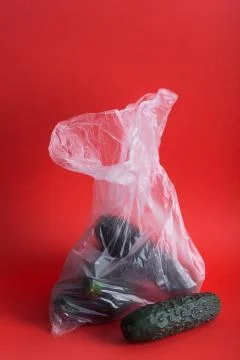 Cucumbers in plastic bag on a red background Fotos Stock