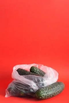 Cucumbers in plastic bag on a red background 写真素材