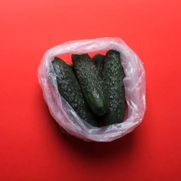 Cucumbers in plastic bag on a red background Stock Photos