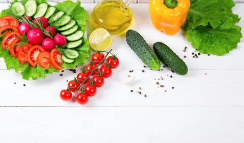 Cucumbers, radish, tomatoes cherry, olive oil, herb and spices on old white w Stock Photos