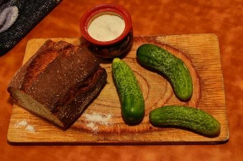 Cucumbers on the table and cutting board next to salt shaker on the table light Stock Photos