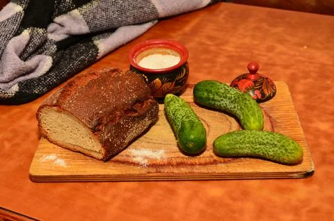 Cucumbers on the table and cutting board next to salt shaker on the table light Stock Photos
