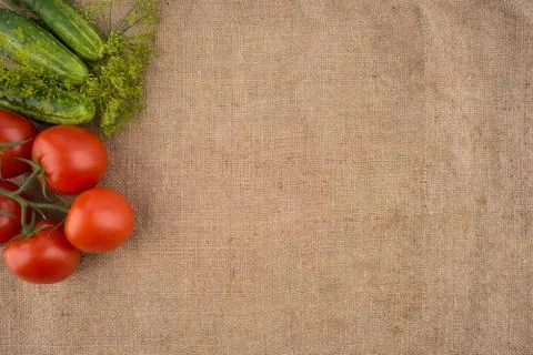 Cucumbers, tomatoes on the background of old sacking. Stock Photos