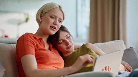 Cuddling lesbian pair talking together using tablet at home closeup. Lgbt couple Stock Footage 335160603