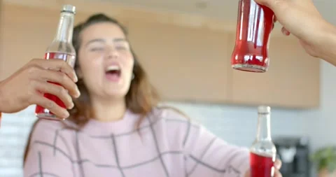 On cue, diverse friends clinking bottles in kitchen celebrating toast, sipping Stock Footage 336844487
