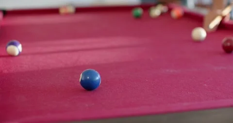 Cue is striking white ball, sending blue ball rolling on magenta-felt table as Видео 335906891