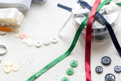 Cufflinks, Sewing Materials, Colorful Threads, and Scissors on a White Surface Foto stock